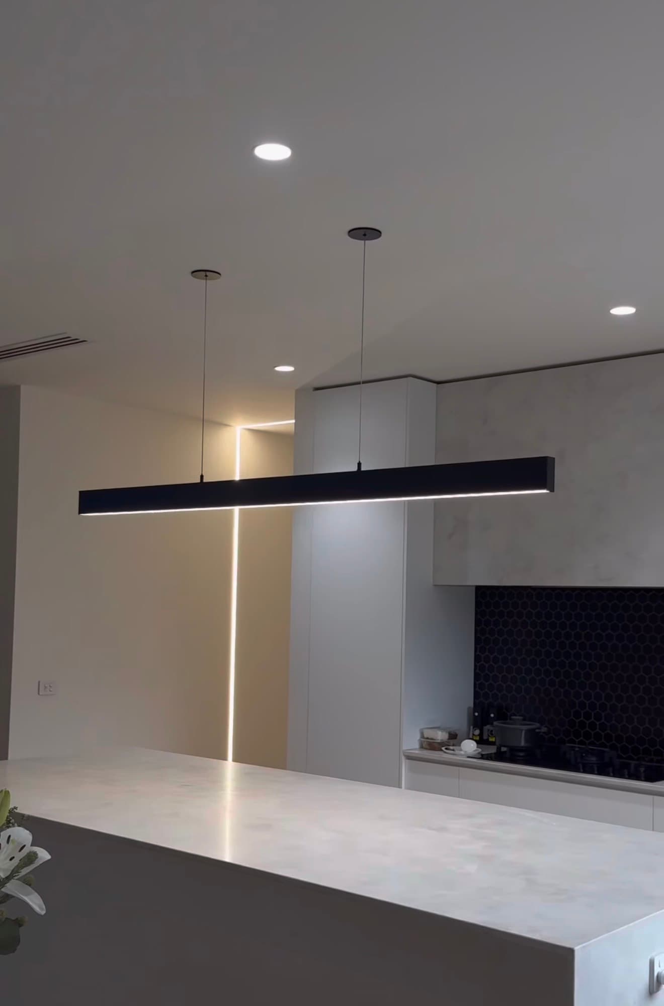 Modern kitchen with black linear pendant light and recessed LED downlights